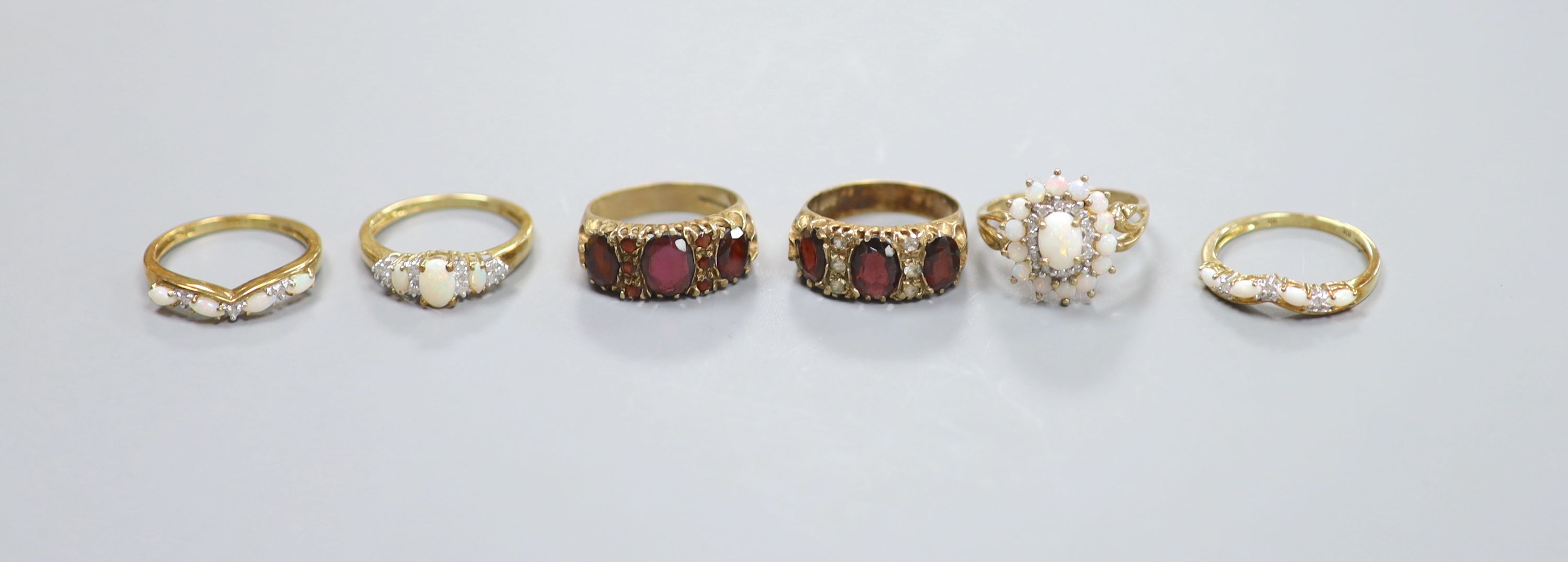 A suite of three opal and 9ct gold rings and three other 9ct gold gem-set rings